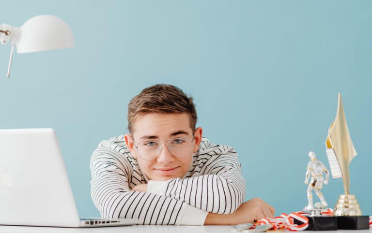 un élève détendu à son bureau où est posé un ordinateur et des figurines évoquant les loisirs