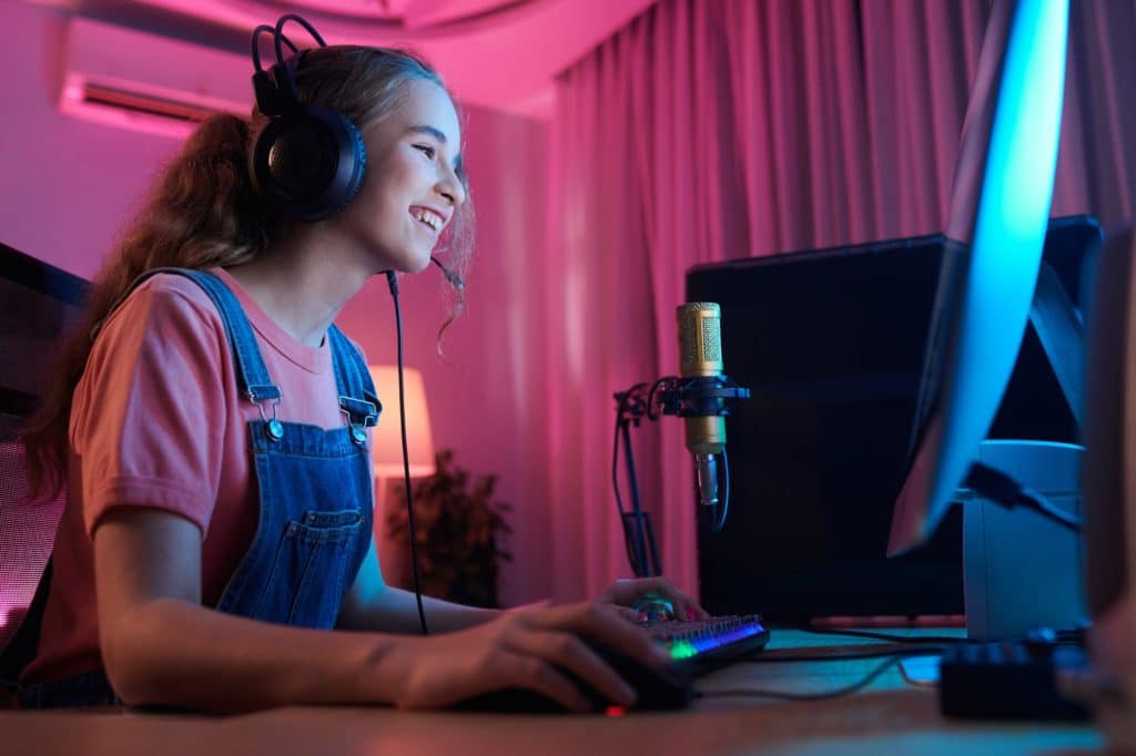 Jeune fille avec casque joue à un jeu vidéo face à un ordinateur