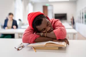 un étudiant dort sur ses livres durant un cours
