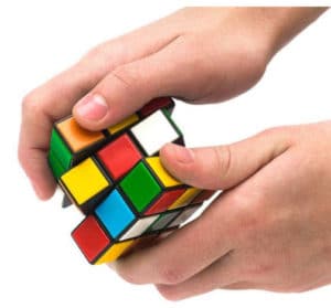 Des mains manipulent en tout sens un jeu de Rubik's cube.