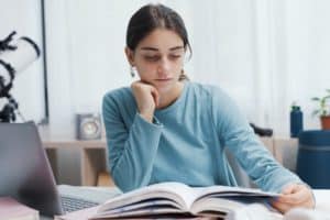 Installée à son bureau devant un livre ouvert, une étudiante a du mal à comprendre ce qu'elle lit.